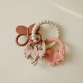 Set of pink baby teething toys with a bow on a beige background
