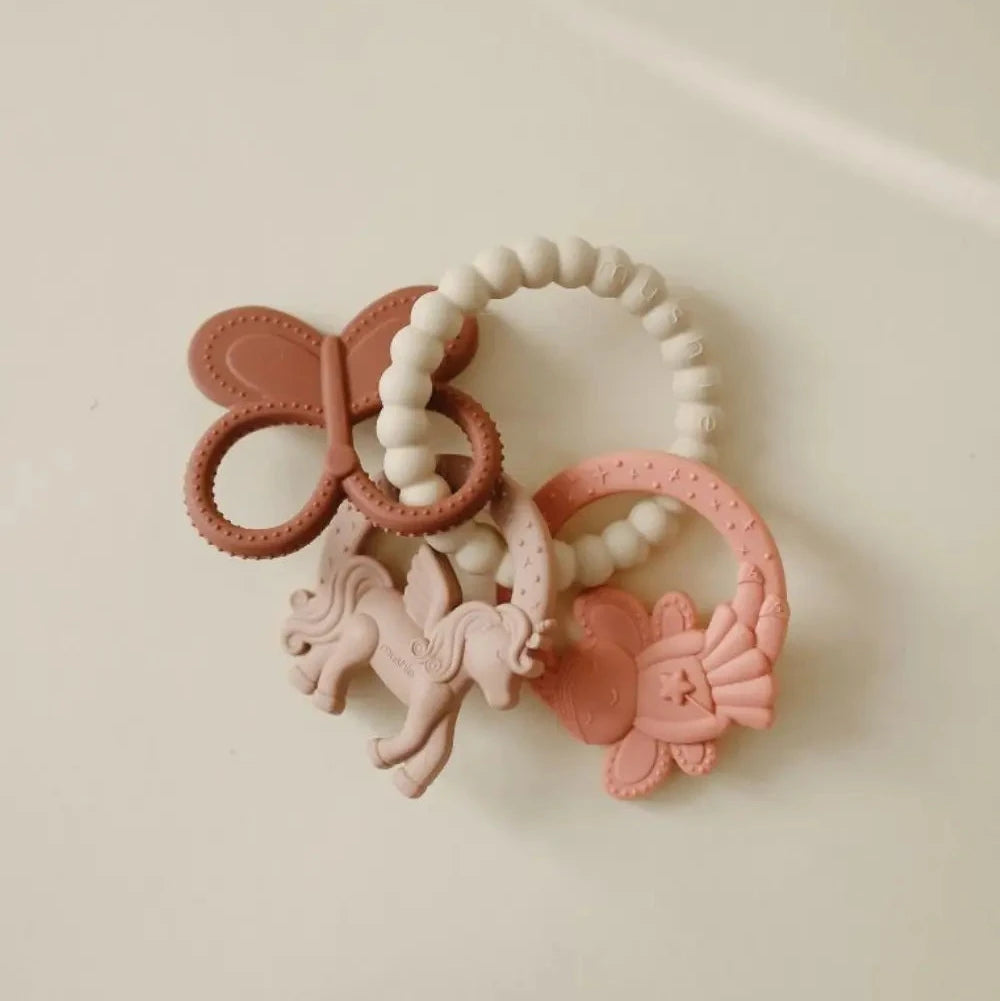 Set of pink baby teething toys with a bow on a beige background